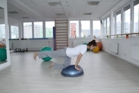 Exercising on a balance device BOSU - stretching legs on all fours
